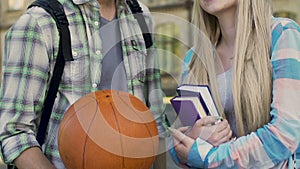 Guy with basketball ball talking to girl with books, popular guy and nerd, flirt