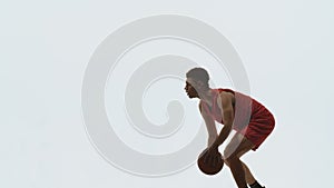 Guy basketball player dribbling ball, hitting it on floor and throws into basket. Young athlete trains before streetball