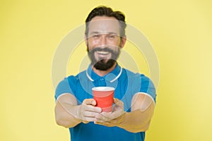 Guy beard and mustache holds paper cup of tea or coffee. Offer drink to you. Trainer experienced man care about water