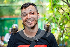 The guy in the bird park communicates with parrots. Tame parrots beg for food from tourists