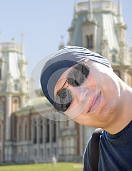A guy in a black bandana and sunglasses takes a selfie against the background of a historic palace