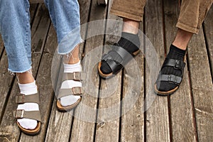 Guy in black socks and girl in white socks on the old wooden floor. both in sandals. close-up photo