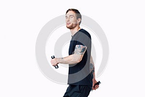 guy in a black t-shirt with dumbbells in his hands on a white background fitness pumped up muscles tattoo