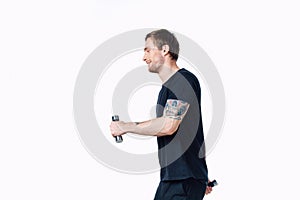 guy in a black t-shirt with dumbbells in his hands on a white background fitness pumped up muscles tattoo