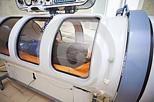 The guy in the black T-shirt lies in the hyperbaric chamber, oxygen therapy photo