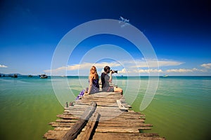 Guy Blond Girl Sit on Wooden Pier Photo Azure Sea in Tropics