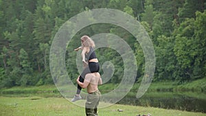 Guy bodybuilder runs around with a girl on his shoulders during a picnic.