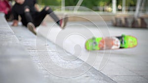 A guy on a bright, colored skateboard, tries to harness onto a concrete staircase and falls. Blurred focus