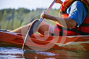 Guy in a canoe holds an oar in his hand. Close-up, side view