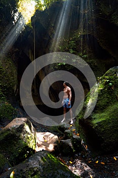 The guy in the canyon the sun`s rays beat into the crevice waterfall Tukad Cepung