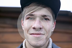 A guy in a cap 21-23 years old model looks smiling at the camera, portrait closeup