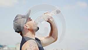 Guy in a cap and with a tattoo is drinking water