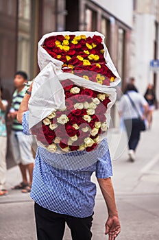 The guy carries a big bouquet with red, white and yellow roses
