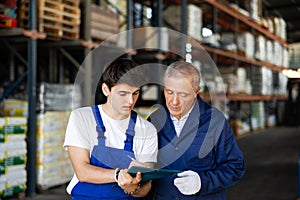 Guy check papers invoices together with mature employee and revise availability of goods in stock