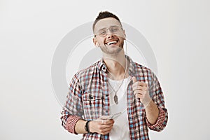 Guy checks out song of singer his friend suggested to listen. Cute slender man in glasses smiling with pleased