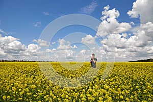 The guy closes his nose and sneezes in the flowering yellow field. Alergy on pollen