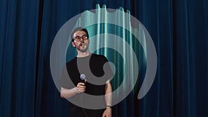 Guy comedian wearing eyeglasses performing his stand up show