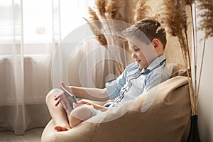 The guy communicates online. Quarantine realities. Communication through a computer. The boy holds a tablet in his hands and