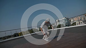 The guy coolly dances breakdance on the roof of the house. A man dances an energetic athletic dance.