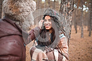 The guy corrects the hat on the girl`s head, the girl smiles . Outdoors in forest.