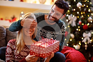 Guy covering his girlfriend`s eyes while giving her present