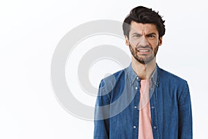 Guy cringe as looking at awful disgusting scene. Displeased, bothered handsome man frowning, feeling sick, express photo