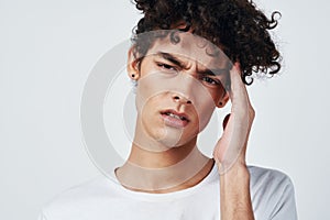 guy with curly hair in a white t-shirt headache migraine discontent