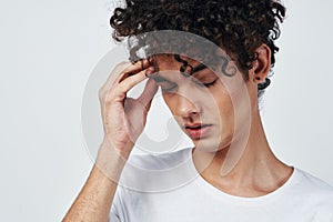 guy with curly hair in a white t-shirt headache migraine discontent