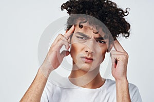 guy with curly hair in a white t-shirt headache migraine discontent