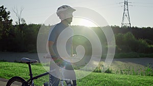 Guy cyclist walks with a bike in the park. Walk after active cycling.