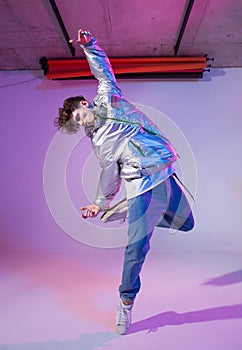 Cool guy dancing contemporary dance in studio. Neon light background. Acrobatic bboy dancer. Break dance lessons.