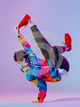 Guy dancing contemporary dance in studio. Neon light grey background. Acrobatic bboy dancer. Break dance lessons.