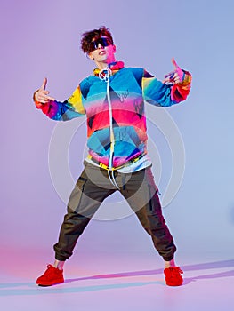 Guy dancing contemporary dance in studio. Neon light grey background. Acrobatic bboy dancer. Break dance lessons.