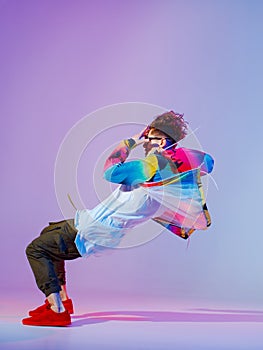 Guy dancing contemporary dance in studio. Neon light grey background. Acrobatic bboy dancer. Break dance lessons. photo