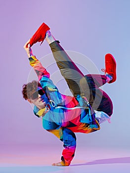 Guy dancing contemporary dance in studio. Neon light grey background. Acrobatic bboy dancer. Break dance lessons. photo