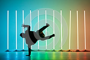 Guy dancing contemporary dance in studio. Neon light tube background. Acrobatic bboy dancer. Break dance lessons. photo