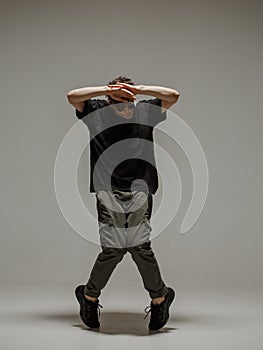 Guy dancing contemporary dance in studio. Neutral grey background. Acrobatic bboy dancer.