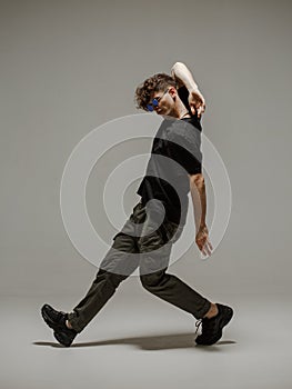 Guy dancing contemporary dance in studio. Neutral grey background. Acrobatic bboy dancer.