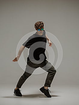 Guy dancing contemporary dance in studio. Neutral grey background. Acrobatic bboy dancer.