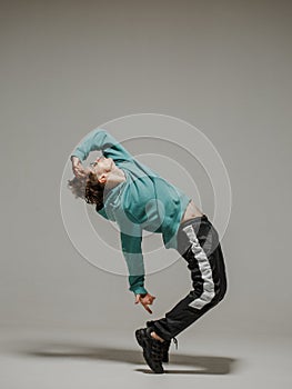 Guy dancing contemporary dance in studio. Neutral grey background. Acrobatic bboy dancer.