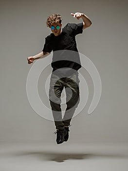 Guy dancing contemporary dance in studio. Neutral grey background. Acrobatic bboy dancer.