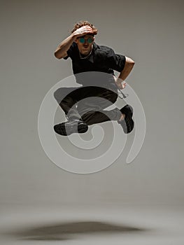 Guy dancing contemporary dance in studio. Neutral grey background. Acrobatic bboy dancer.