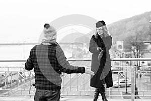 Guy delayed to date. Woman shows times on arm. Man spread his hand out on bridge and walking area