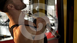 Guy with developed muscles doing pulldown exercise, workout in gym, endurance