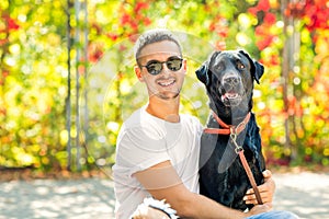 Guy with a dog walks in a park in autumn