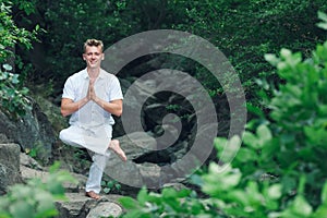 guy doing yoga asana Eka Pada Utkatasana. meditation in nature.