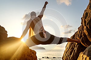 Guy doing yoga at sunset by the sea