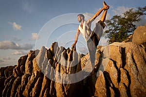 Guy doing yoga at sunset by the sea