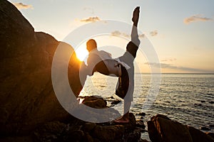 Guy doing yoga at sunset by the sea