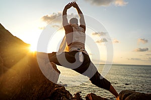Guy doing yoga at sunset by the sea